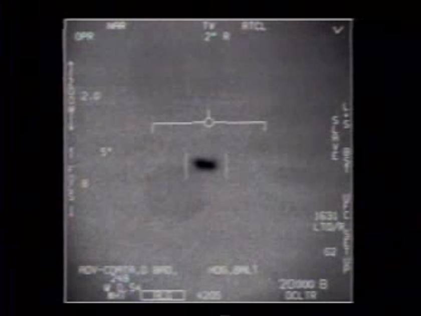 Infrared targeting-camera frame: a small dark oblong shape inside tracking brackets against a grey sky, with cockpit readouts around the edge